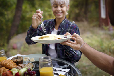 Cropped image of man offering pancakes to young woman during breakfast