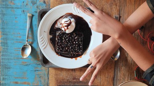 Cropped hands gesturing peace sign over dessert on table