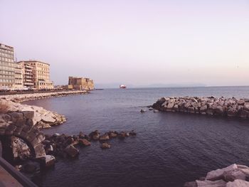 Scenic view of sea by buildings against clear sky