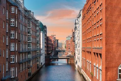 Canal amidst buildings against sky during sunset