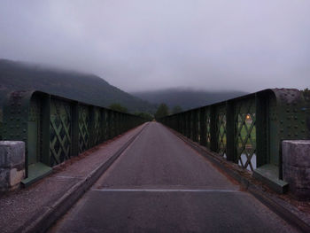 Empty road by bridge against sky