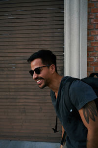 Portrait of young man wearing sunglasses standing against brick wall