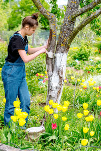 Side view of woman standing by flowering plants