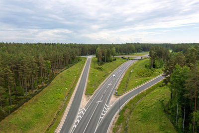 Panoramic shot of road amidst trees on field against sky