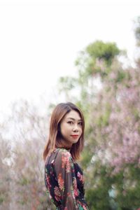 Young woman standing against tree