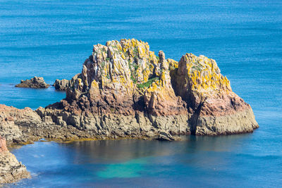 Rock formation in sea against blue sky