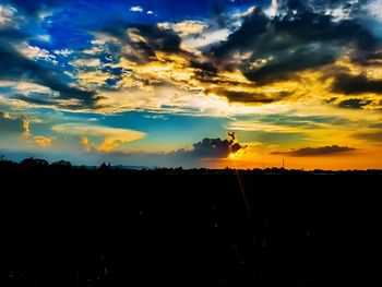 Scenic view of silhouette landscape against dramatic sky during sunset