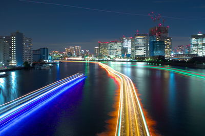 Illuminated light trails amidst buildings in city at night