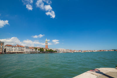 View of building by sea against blue sky