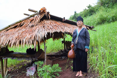 Full length portrait of woman holding container while standing on field