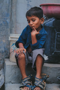 Boy looking down while sitting on staircase