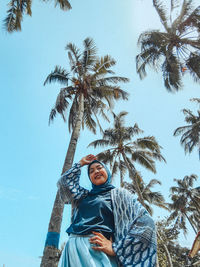 Low angle view of woman with palm tree