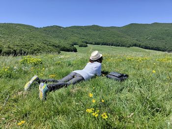 Rear view of woman sitting on grassy field