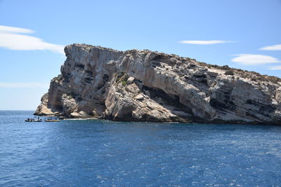 Rock formations by sea against blue sky