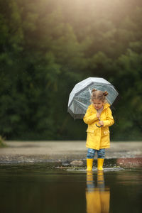 A girl in yellow boots walks through the puddles