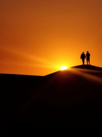 Silhouette people standing on street against sky during sunset