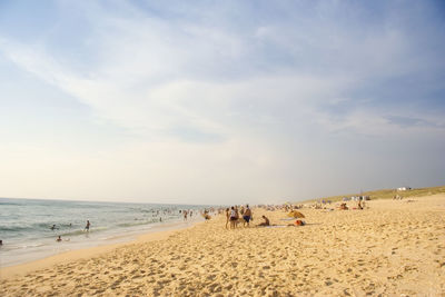 People at beach against sky