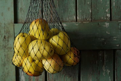 Close-up of fruits hanging on wood against wall