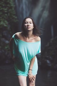 Portrait of woman standing against waterfall