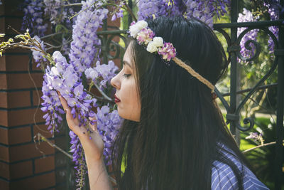 Close-up of woman smelling flowers on gate