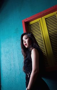 Beautiful young woman standing against wall