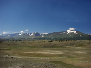 Scenic view of snowcapped mountains against blue sky