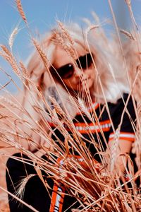 Woman in sunglasses sitting amidst wheat plants