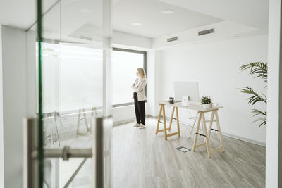 Businesswoman in modern office looking out of window