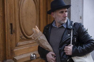 Adult man in hat holding bread and vegetable bag on street. madrid, spain