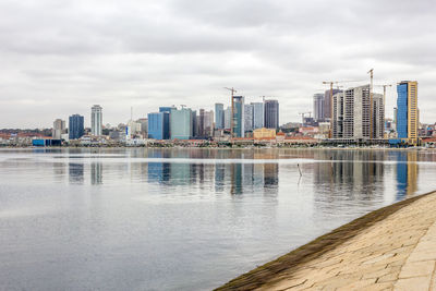 Sea by cityscape against sky