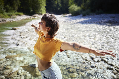 Smiling woman standing with arms outstretched on sunny day