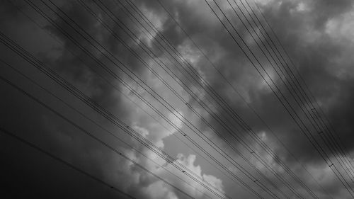 Low angle view of birds flying against cloudy sky
