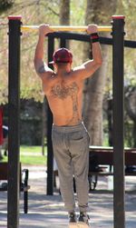 Rear view of shirtless man exercising outdoors