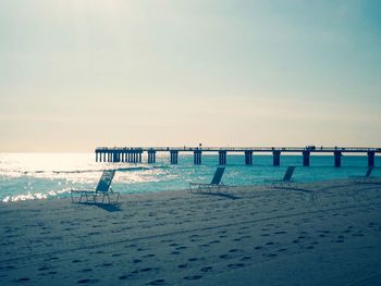 Wooden posts on beach against clear sky