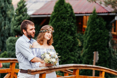 Couple holding bouquet standing outdoors