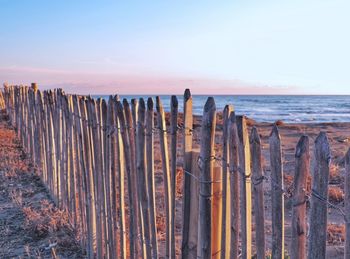 Wooden posts on beach against sky