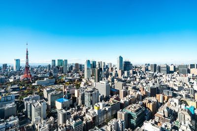Aerial view of buildings in city against clear blue sky
