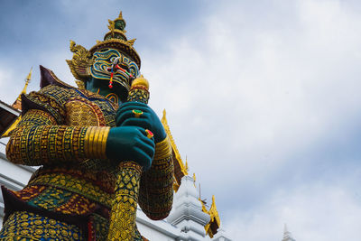 Low angle view of statue against temple building against sky