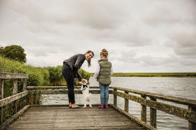 Full length of friends standing on water against sky