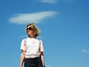 Portrait of woman standing against blue sky