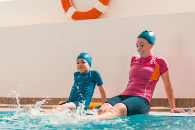 Boy learning to swim in pool with teacher