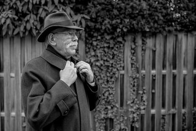 Portrait of man standing by fence