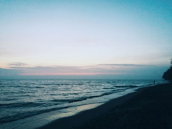 Scenic view of beach against clear sky at sunset