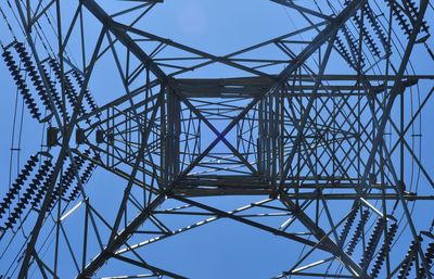 Low angle view of electricity pylon against blue sky