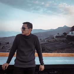 Young man standing on mountain against sky