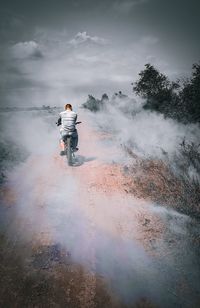 Man riding bikecycle on land against sky