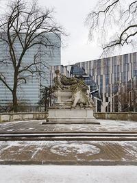 Statue in city against sky during winter