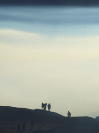 Silhouette people standing on mountain against sky during sunset