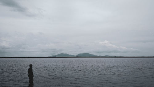 Man standing in sea against sky