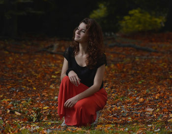 Young woman crouching on field during autumn